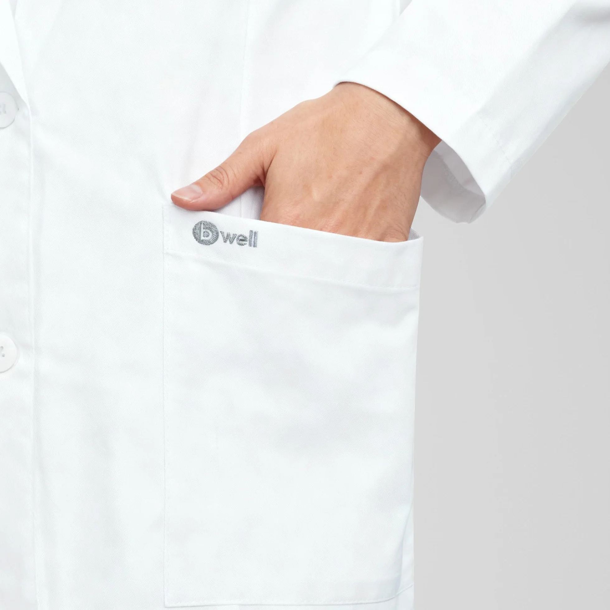 B-well Livia - Bata médica corta para mujer, color blanco, con cuello de solapa, manga larga, 3 bolsillos, tira de botones, para enfermería y clínica
